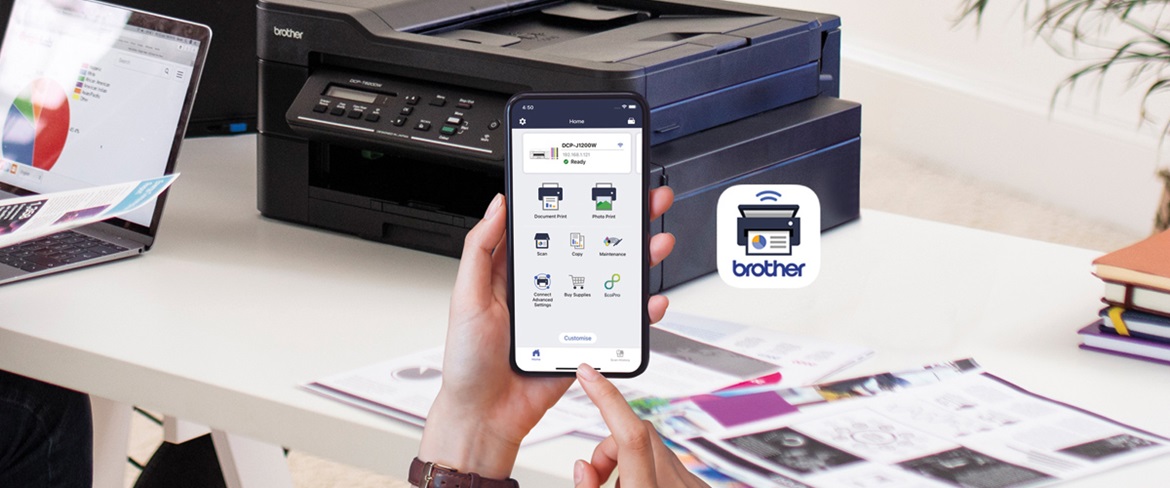 Une application Brother pour l'impression mobile sur un téléphone, avec en arrière-plan une imprimante Brother noire sur un bureau.