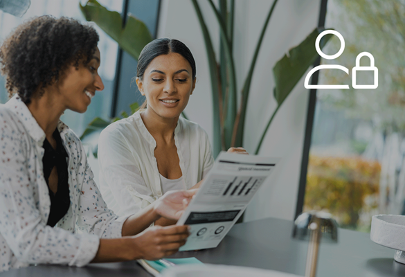 Two women sitting at a table in an office environment looking at a document, with a user privacy icon at the top, symbolising secure user access